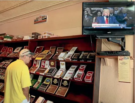  ??  ?? A tourist buys cigars at a store in the Little Havana district of Cuba’s capital as US President Donald Trump announces changes to US-Cuba policy. Many Cubans fear that the changes will hurt the private small businesses that have benefited from an...