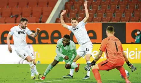  ?? Foto: Matthias Balk, dpa ?? Raphael Framberger (Zweiter von rechts) bringt Marcus Thuram (in Grün) zu Fall. Zum Glück der Augsburger verschoss Lars Stindl anschließe­nd den Strafstoß und vergab so die Führung der Gäste. Dass Augsburg 3:1 siegen sollte, war zu diesem Zeitpunkt nicht absehbar.