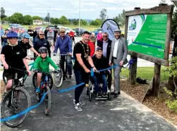  ?? Photo by Central South Trail. ?? Above: A crowd is gathered with children and adults on bikes, a man in a wheelchair, and a few onlookers, while a man in mayoral chains cuts a ribbon for the new trail.