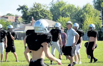  ??  ?? Bernie Tessier, white and sunglasses, head coach of the Lakeshore Catholic senior football team, leads prospects through a conditioni­ng drill on the opening day of tryouts Monday in Port Colborne.