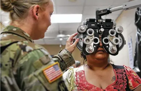  ?? Bob Owen / San Antonio Express-News ?? Irma Sanchez, 38, of Laredo, has her eyes checked by Maj. Jennifer Meadows on Tuesday in a mobile clinic set up in the El Cenizo Community Center in El Cenizo. The Army and students from Texas A&M have been working together on health care training.