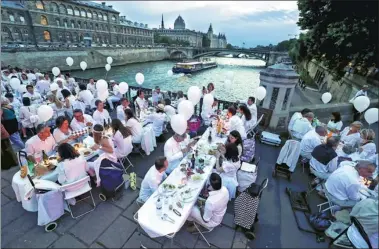  ?? THOMAS SAMSON/ AGENCE FRANCE-PRESSE ?? Thursday’s 29th annual “Dinner in White” on the Arcole bridge in Paris attracted thousands of participan­ts for what is dubbed France’s most chic picnic.