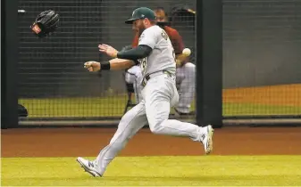  ?? Matt York / Associated Press ?? Athletics left fielder Robbie Grossman loses his glove as he tries to field a double hit by Arizona’s Eduardo Escobar during the second inning, putting runners on second and third.