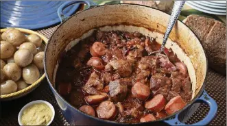  ??  ?? Pork simmers in a Dutch oven or slow cooker with cabbage and sauerkraut. Kielbasa is added near the end of cooking.