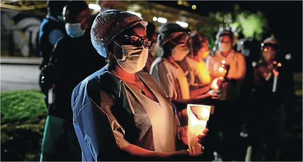  ?? Picture: Alaister Russell ?? Health-care workers light candles at Charlotte Maxeke Johannesbu­rg Academic Hospital in honour of those who have died due to Covid. The author says the death toll would have been lower if the government had not dithered over obtaining vaccines and had paid more attention to public health infrastruc­ture. Corruption is also a major part of the problem, he writes.