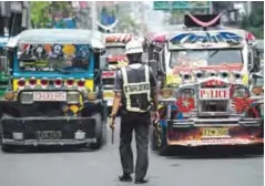  ??  ?? MANILA: Jeepneys are seen as an enforcer manages traffic on a busy street yesterday. — AFP