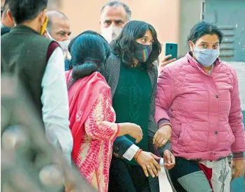  ?? — AFP ?? Police officers in plain clothes escort environmen­t activist Disha Ravi (C) to a local court in New Delhi on on Friday.