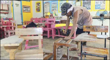  ?? GERRY LEE GORIT ?? A carpenter repairs the desks in a classroom at the Looc Elementary School in Villanueva, Misamis Oriental yesterday.