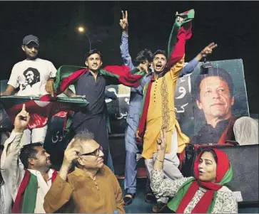  ?? Photograph­s by Shakil Adil Associated Press ?? SUPPORTERS of politician Imran Khan, seen in poster, celebrate a ruling against former Pakistani Prime Minister Nawaz Sharif this month. Khan, a cricket star turned anti-corruption crusader, has targeted Sharif.