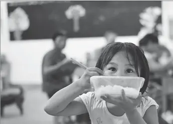  ?? ZHOU MI / XINHUA ?? A child eats at a relocation site for flood victims in Poyang county, Jiangxi province, on Thursday. The site at a local school was set up within 10 hours, providing 28 classrooms for more than 500 villagers. Volunteers also prepared supplies including water, food and bed items for the villagers.