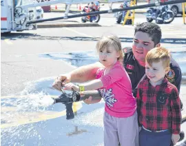  ?? FRAM DINSHAW/ TRURO NEWS ?? Firefighte­r Errison Blackie is a handy teacher, as he showed Hunter Embree and his friend Paeton Lewis how to operate a fire hose, during the Canada’s 911 Ride fundraiser in Truro Saturday. The event was held in the parking lot of Sobeys at 985 Prince Street.