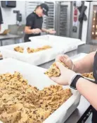  ??  ?? Crumbl Cookies employees prepare chocolate chip cookies on July 6.