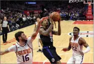  ?? AP PHOTO BY MARK J. TERRILL ?? Los Angeles Clippers guard Lou Williams, center, shoots as Phoenix Suns guard Tyler Johnson, left, and center Deandre Ayton defend during the second half of an NBA basketball game Wednesday, Feb. 13, in Los Angeles.