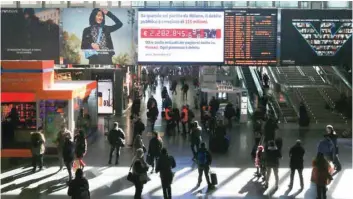  ?? — Reuters ?? People walk past a ‘debt clock’ screen displaying Italy’s public debt at the Termini central station in Rome, Italy.