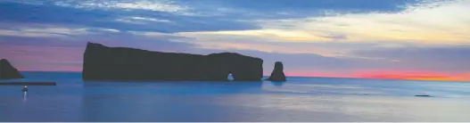  ??  ?? The sun begins to rise over the arched stone — 90 metres wide and 88 metres high — at Percé Rock, which was once connected to the mainland and is now the symbol of maritime Quebec.