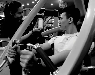  ?? XINHUA ?? A fitness program consumer checks readings on an app while exercising at a club in Beijing.
