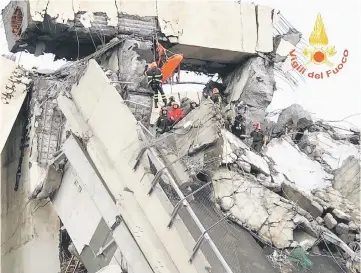  ??  ?? Photo shows rescuers at work amid rubble and wreckage after the collapse of a section of the Morandi motorway bridge. — AFP photo