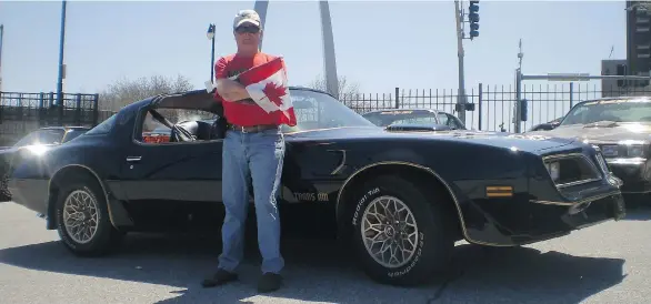  ??  ?? Canadian flag in hand, David Holmes takes a break with his 1977 Special Edition Pontiac Trans Am in St. Louis, Mo., during the annual movie-commemorat­ing ‘Bandit Run’ event.