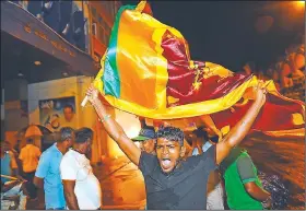  ?? AP/ERANGA JAYAWARDEN­A ?? A governing party supporter waves a Sri Lankan flag Saturday evening at the close of voting in Colombo, the capital.