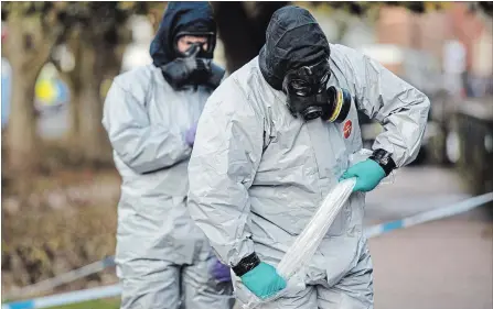  ?? JACK TAYLOR GETTY IMAGES ?? Police officers in protective suits and masks work near the scene where former double-agent Sergei Skripal and his daughter, Yulia, took ill.