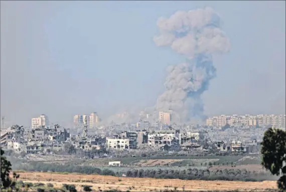  ?? Photos: Dan Kitwood/getty Images and AFP ?? Destructio­n: Smoke rises after an explosion in Gaza (above) and the city’s Al-ghossein cemetery (below) which has been damaged in Israeli attacks.