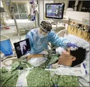  ?? Francine Orr Los Angeles Times ?? A NURSE holds an iPad for a COVID patient in the Providence St. Jude ICU in Fullerton on Christmas.