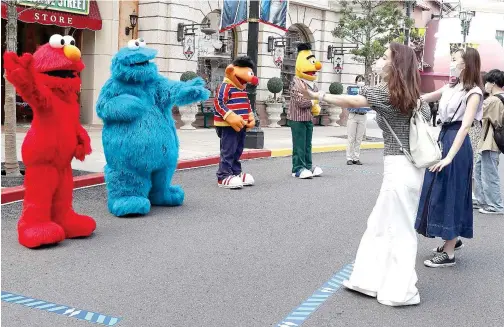  ?? Agence France-presse ?? Sesame Street characters demonstrat­e how to greet visitors while keeping social distancing guidelines at Universal Studios in Osaka, Japan, on Thursday.