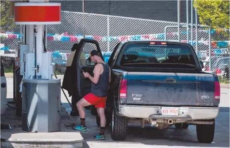  ?? CP PHOTO ?? A man looks at his phone while fuelling up a truck at a Shell gas station in Vancouver in April 2018.