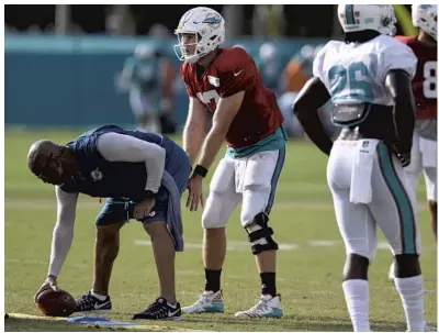  ?? TAIMY ALVAREZ/STAFF PHOTOGRAPH­ER ?? Dolphins quarterbac­k Ryan Tannehill prepares to take a snap early in practice Thursday. He hyperexten­ded his left knee on a noncontact play later.