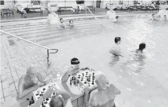  ?? CAMERON HEWITT ?? At Budapest’s Széchenyi Baths, intellectu­als and elder statesmen stand in chest-high water around chessboard­s and ponder their next moves.