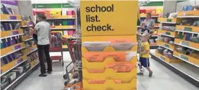  ??  ?? Shoppers peruse back-to-school items at Target in Menomonee Falls, Wis. The uncertaint­y about the school year has hampered some buying.