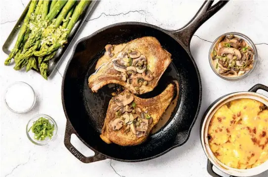  ?? EBERLY FILM LAB/THE DAILY MEAL PHOTOS ?? For your holiday meal, serve pork chops with a sauce of baby portabella mushrooms, along with creamy potato gratin and steamed asparagus.