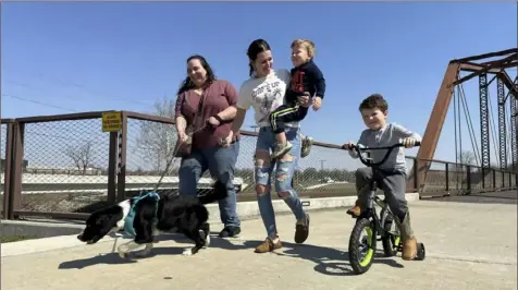  ?? Isabella Volmert/Associated Press ?? Emerson Howard, left, and her dog, Dixie, enjoy a walk along with Destiny Porter and her children, 2-year-old Merrick Mercer and 4-year-old Maxton Mercer, on the bridge connecting trails in Muncie, Ind., earlier this month.