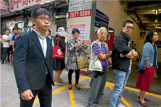  ?? AP ?? Pro-democracy activist Joshua Wong walks past people lined up to vote outside of a polling place in Hong Kong yesterday.