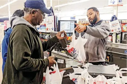  ?? [PHOTOS BY CHRIS LANDSBERGE­R, THE OKLAHOMAN] ?? Owner Marcus Scarboroug­h helps customer Anthony Pitre in a checkout line at the new Save-A-Lot food store located at 1124 NE 36 in Oklahoma City. Scarboroug­h and his co-owners build grocery stores in areas that have no access to fresh produce and meats.