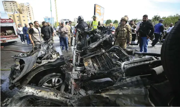  ?? EPA ?? A crowd gathers near the burnt wreckage of a vehicle hit in an Israeli strike near the coastal city of Tyre, southern Lebanon, in which a Hamas member was killed