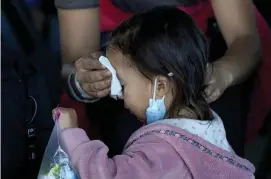  ??  ?? TOUGH TRIP: A migrant woman cleans the face of a child at a respite center after the family was released from U.S. Customs and Border Protection custody Saturday in Brownsvill­e, Texas.