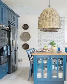  ??  ?? This kitchen features a L-shaped perimeter design with lower cabinets painted a rich shade of navy blue, a style choice that has become increasing­ly popular.