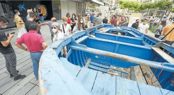  ??  ?? La embarcació­n rescatada en el Estrecho de Gibraltar como parte de la exhibición. Al fondo una de las lonas con la fotografía de David Beriain.