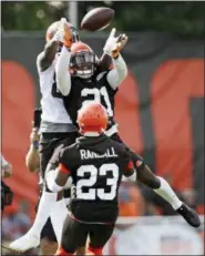  ?? TONY DEJAK — THE ASSOCIATED PRESS ?? Cleveland Browns defensive back Denzel Ward, center, grabs a pass under pressure from wide receiver Jarvis Landry, top, during an NFL football training camp, Thursday in Berea, Ohio.