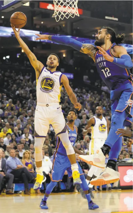  ?? Carlos Avila Gonzalez / The Chronicle ?? Stephen Curry goes up for a shot against Steven Adams of the Thunder in the Warriors’ 108-100 opening night win.
