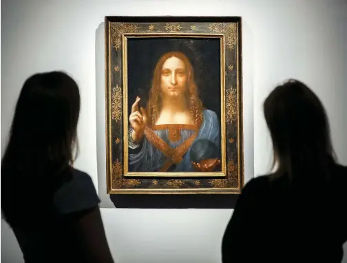  ?? PHOTO AFP ?? Des employés de la maison Christie’s posent devant le tableau Salvator Mundi réalisé par Léonard de Vinci vers 1500.