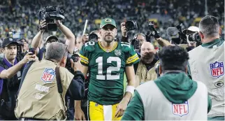  ?? MIKE ROEMER/THE ASSOCIATED PRESS ?? Green Bay quarterbac­k Aaron Rodgers leaves the field surrounded by photograph­ers after his fourth quarter heroics led the Packers to a 24-23 win over the Chicago Bears Sunday.