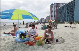  ?? JEFFREY COLLINS — THE ASSOCIATED PRESS ?? Christy Kasler, center, from Ohio, enjoys a day at the beach last week while her daughter-in-law Cory plays with her grandson, Bentley, in Myrtle Beach, S.C. Across America, people are leaving their cares — and sometimes their masks — at home after months of worry about the virus as Southern states like South Carolina open hotels and restaurant­s and like Myrtle Beach advertise “Yes, the beach is open!”