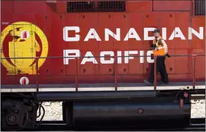  ?? CP FILE PHOTO ?? A Canadian Pacific Railway employee walks along the side of a locomotive in a marshallin­g yard in Calgary. Canadian Pacific Railway is demanding that crude-by-rail shippers sign multi-year take-or-pay contracts that guarantee volumes before it will...