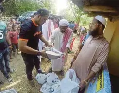  ??  ?? MUHAMMAD Amir (kiri) menyerahka­n bantuan pengagihan fidyah berbentuk beras pada Program Prihatin Ummah Ramadan.