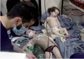  ??  ?? Sopravviss­uti Un volontario cura due bambini che hanno respirato gas a Douma, accusando difficoltà a respirare e bruciore agli occhi