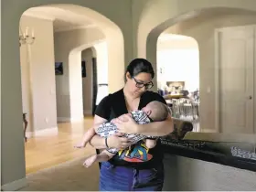  ?? Guy Wathen / The Chronicle ?? Melissa Geissinger holds son Ollie at her parents’ home in Sebastopol where she and husband Cole are staying till moving to a rental home in Bodega Bay.