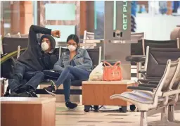  ?? ROSS D. FRANKLIN/AP ?? Two passengers wearing face coverings wait for a flight at Phoenix Sky Harbor Internatio­nal Airport on April 14 in Phoenix. The coronaviru­s outbreak has caused a significan­t decrease in air travel.