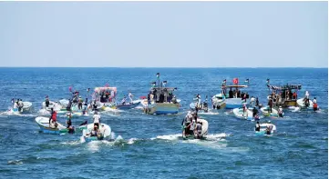  ??  ?? People ride boats as a boat carrying Palestinia­n patients and students sails towards Europe aiming to break Israel’s blockade on Gaza, at the sea in Gaza. — Reuters photo